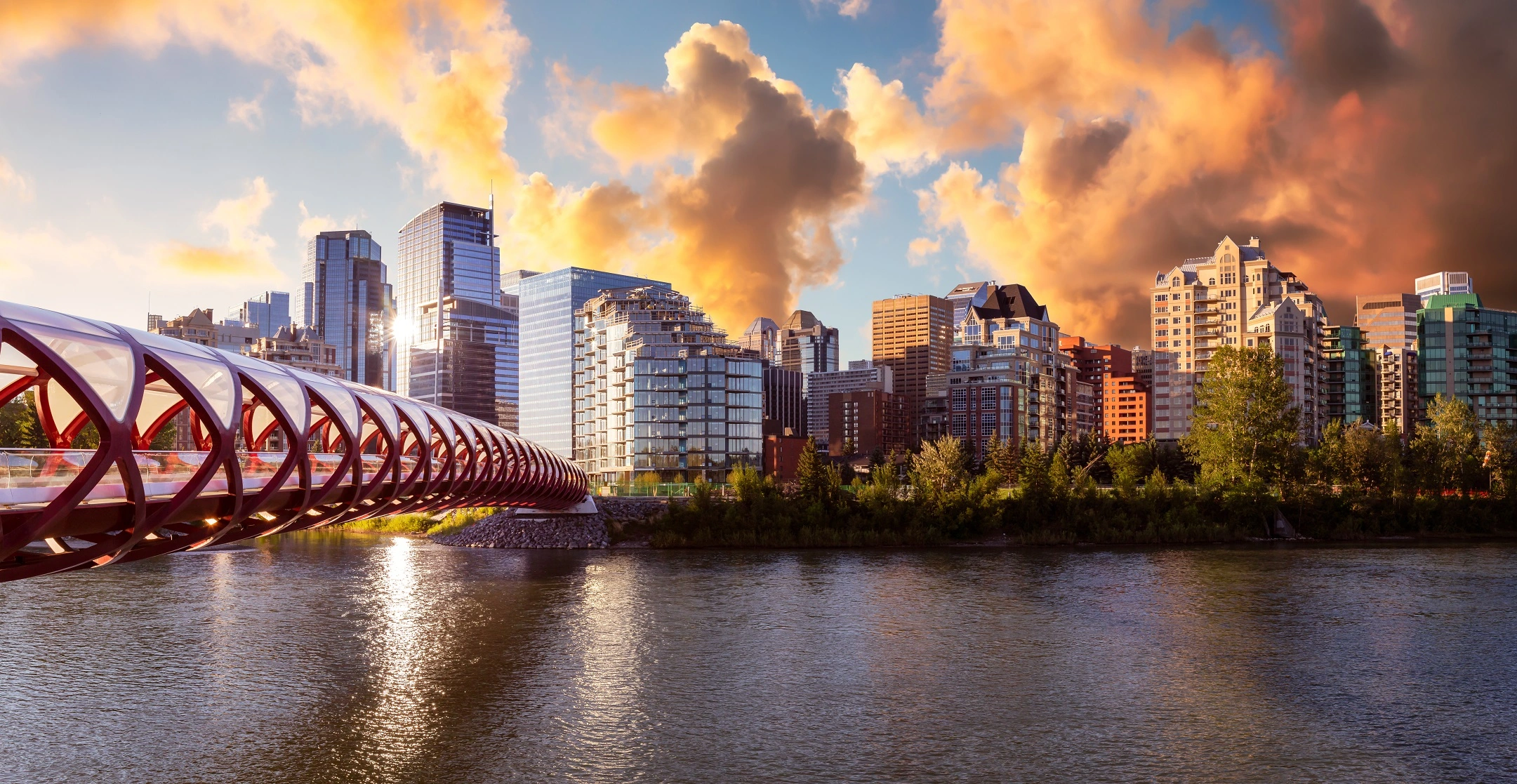 Skyline de Calgary, Alberta, Canadá, com a Peace Bridge ao pôr do sol, simbolizando as cidades vibrantes e modernas disponíveis para imigrantes
