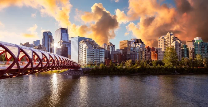 Skyline de Calgary, Alberta, Canadá, com a Peace Bridge ao pôr do sol, simbolizando as cidades vibrantes e modernas disponíveis para imigrantes