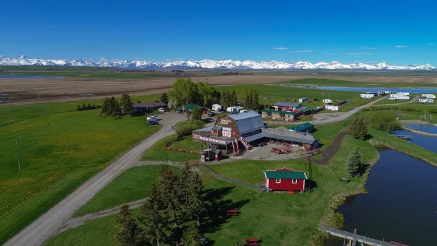 Paisagem rural no Canadá com rancho em Alberta e as Montanhas Rochosas ao fundo, representando qualidade de vida e oportunidades para imigrantes